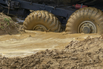 big wheels in the mud. The large wheels of a truck stuck in the mud.