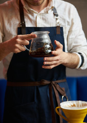 Barista pouring hot coffee into a cup, close-up