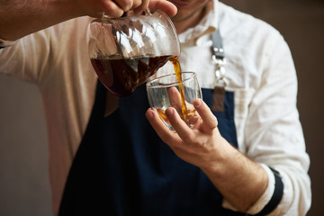 Barista pouring hot coffee into a cup, close-up