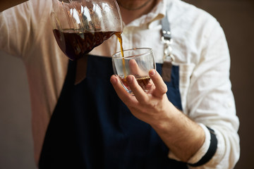 Barista pouring hot coffee into a cup, close-up