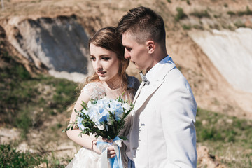 Wedding ceremony in the mountains. The bride and groom standing in front of the sandy mountains. The happy couple, a beautiful wedding in a picturesque location