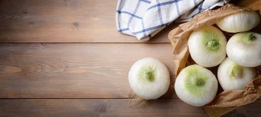 Onion flat white with paper bag on wood background. Top view, space for text
