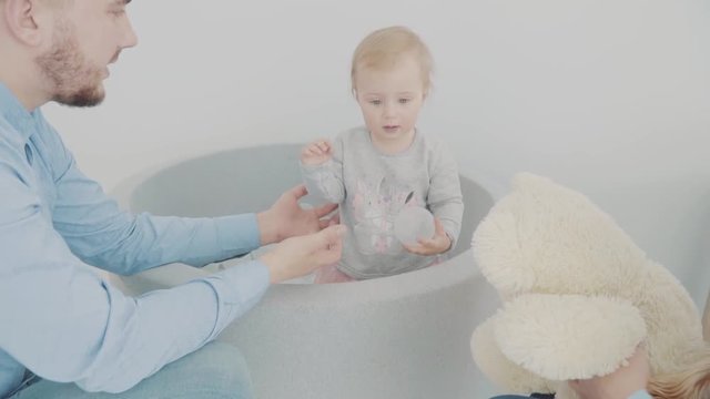 Beautiful little girl play with her father in pool with balls. Slow-motion