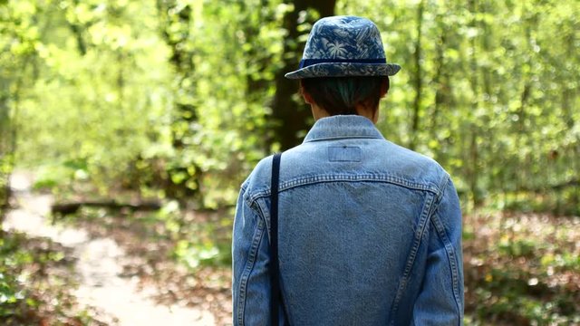 Young woman in hat walking in the tree forest