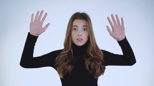Portrait of shocked guilty girl raising hands on background