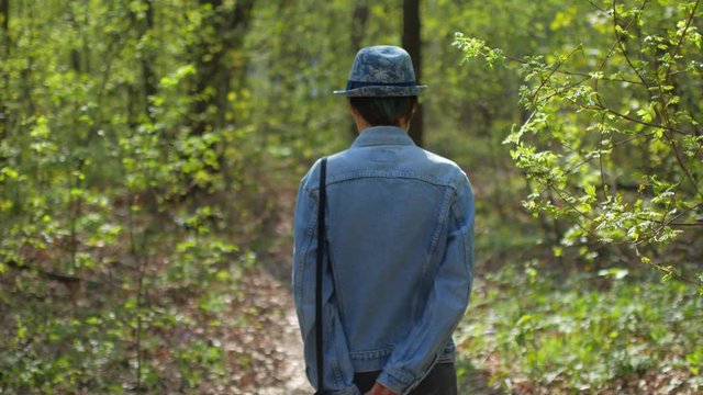 Young woman in hat walking in the tree forest