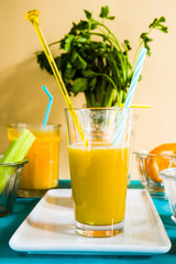 healthy Apple , lemon  and celery juice on a white plate over a blue board and against a yellow pale background.