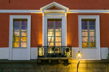 Fototapeta na wymiar Three windows and a balcony on night, lightd by a lamp post