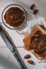 toast bread with chocolate and knife on white wooden table