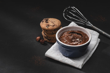 bowl with chocolate dessert, whisk and cookies on tabletop