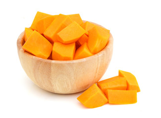 A group of cut and slice butternut squash chunks in wooden bowl on a white background.
