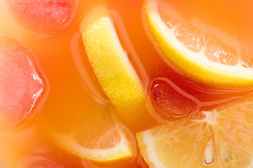 close up view of fresh cocktail with ice cubes and lemon pieces background