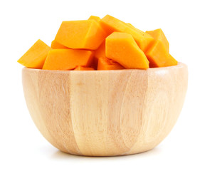 A group of cut and slice butternut squash chunks in wooden bowl on a white background.