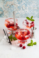 summer alcoholic drink with raspberry liqueur, ice and leaves of fresh mint on the table. bar accessories.