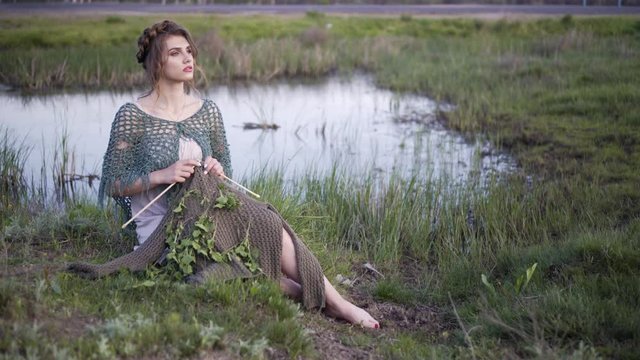 Fantasy girl enjoying light evening breeze at quiet lakeshore. Magical moves of innocent nymph of the wilds
