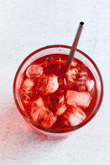 red drink with ice cubes in a glass with a straw. close-up shot