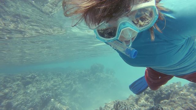 Female Snorkeler Wearing UV Protection Clothes, Admiring A Big Heliopora Blue Coral In The Shallow Turquoise Waters Of The Maldives.