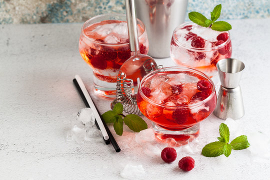 summer alcoholic drink with raspberry liqueur, ice and leaves of fresh mint on the table. bar accessories.