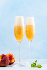 two glasses of champagne with a cocktail of Bellini and fresh peaches on a blue background. summer refreshing drink