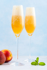two glasses of champagne with a cocktail of Bellini and fresh peaches on a blue background. summer refreshing drink
