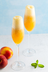 two glasses of champagne with a cocktail of Bellini and fresh peaches on a blue background. summer refreshing drink