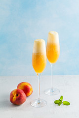 two glasses of champagne with a cocktail of Bellini and fresh peaches on a blue background. summer refreshing drink