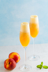 two glasses of champagne with a cocktail of Bellini and fresh peaches on a blue background. summer refreshing drink