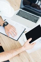 partial view of person wearing smartwatch and using digital tablet at workplace