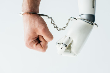 close-up view of human hand and hand of robot in handcuffs isolated on white
