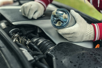 An auto mechanic replaces a car's fuel filter.