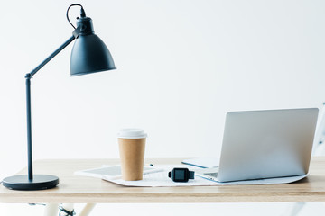 smartwatch, laptop and disposable coffee cup at workplace