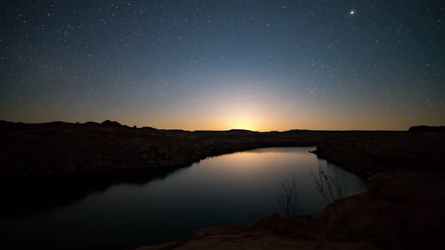 Time lapse of the moon rising over lake in the desert viewing stars reflecting in Lake Powell in Utah.