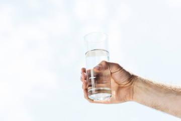 cropped shot of human hand holding glass of fresh water
