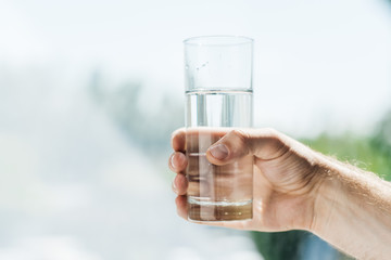 close-up partial view of person holding glass of fresh water
