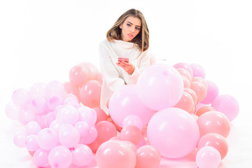Obraz na płótnie Canvas Woman laying with balloons. Pyjama party. Gorgeous trendy young woman laying in pink balloon. Girl in white sweater sits in balloons. Party girl, happy mood, celebration concept.