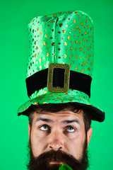 St. Patrick's Day. Bearded man in leprechaun hat. Portrait of pensive man. Clover in mouth.