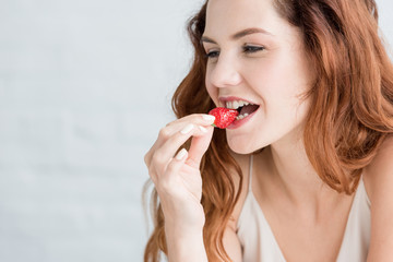 close-up portrait of beautiful young woman eating strawberry