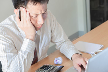 Young Asian Businessman having headache while he work overtime. Frustrated stressed business man in...