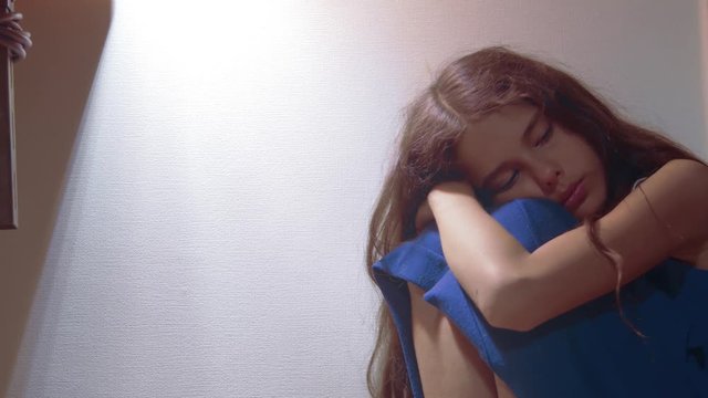 sad girl upset embraces her feet. is depressed and suicidal little lamentable girl schoolgirl sadness misses the night in bed concept childhood family. the problem of education in the family lifestyle