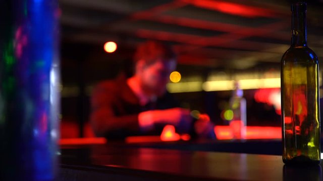 Depressed young man drinking alcohol alone in bar, failure, problems in life