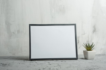 Empty white frame with flower on wall background. The concept of design and font inscriptions and image placement