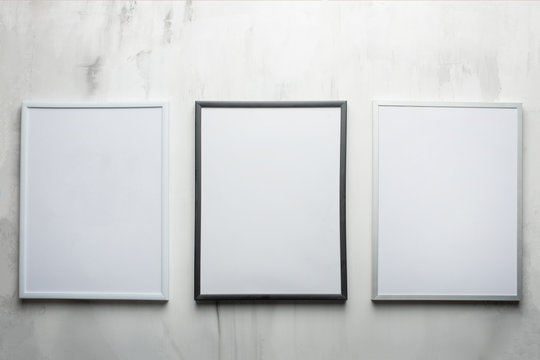 Three white frames on the wall background. The concept of design and font inscriptions and image placement