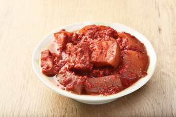 Braised pork with red yeast on the wooden table  