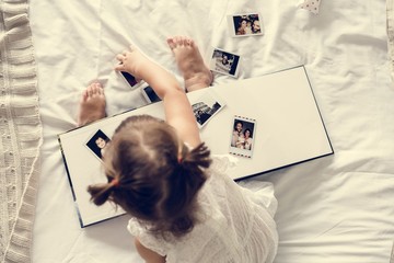 Little girl playing with a photo album - obrazy, fototapety, plakaty