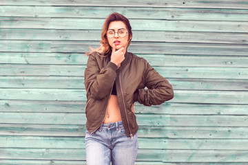 fashion girl posing near a turquoise wooden wall