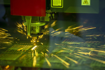 Close-up of the CNC laser cutting machine cutting the metal plate with the sparking light. Modern...