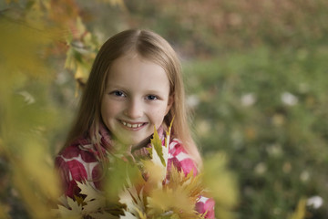 Portrait of a Happy smiling little girl looking at the camera in the autumn park. Cute four years old child enjoying nature outdoors.
