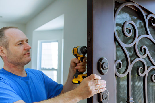 The carpenter installs a reliable resistant lock in the metal door.