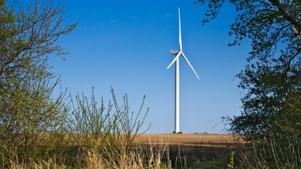 Windmill for electric power production in farm country at dusk