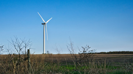 Fototapeta premium Windmill for electric power production in farm country at dusk